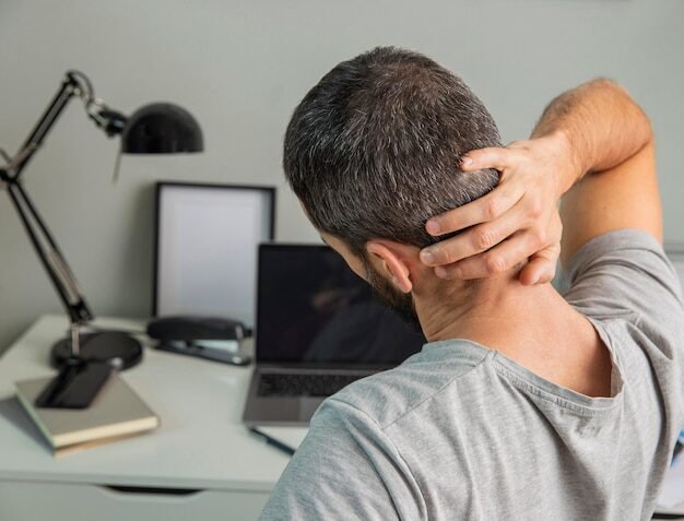 Vista traseira de um homem se alongando enquanto trabalhava em casa